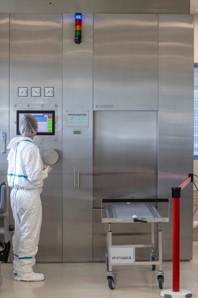 Person in protective gear operating a sterilization machine in a lab