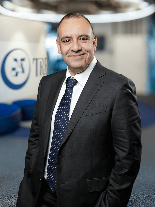 Alessandro Di Napoli, smiling in a suit, standing in an office setting