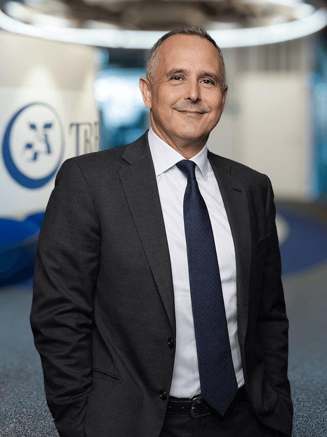 Man in a suit smiling, standing in an office environment