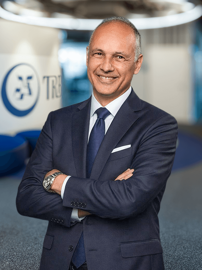 Karim Husny smiling in a suit with arms crossed