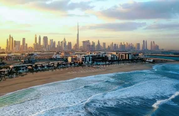 Dubai skyline at sunset with beach and waves in the foreground