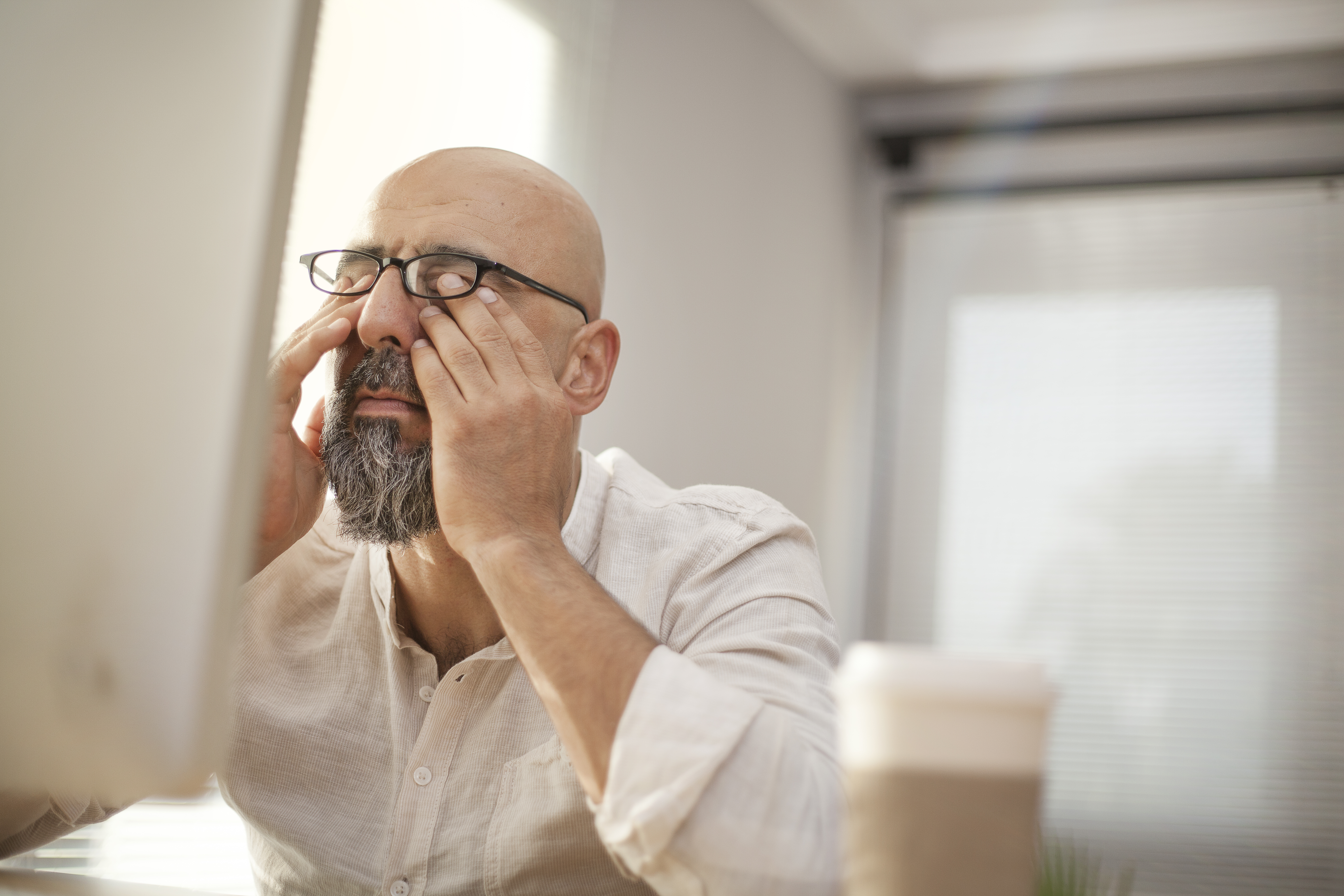 Senior businessman rubbing his eyes while sitting at a desk