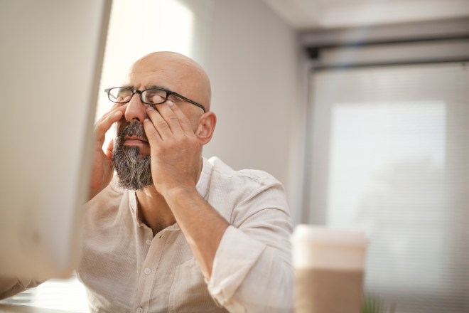 Senior businessman rubbing his eyes while sitting at a desk