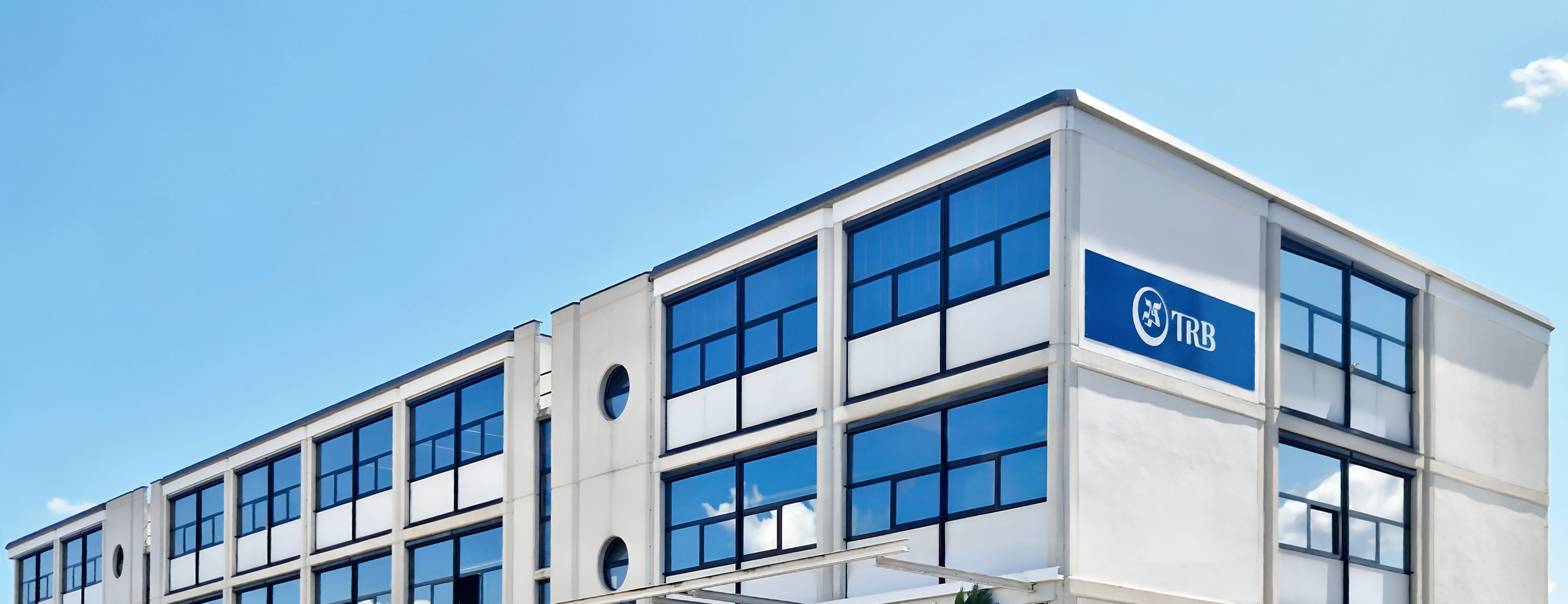Exterior view of a modern building with large windows and a TRB logo