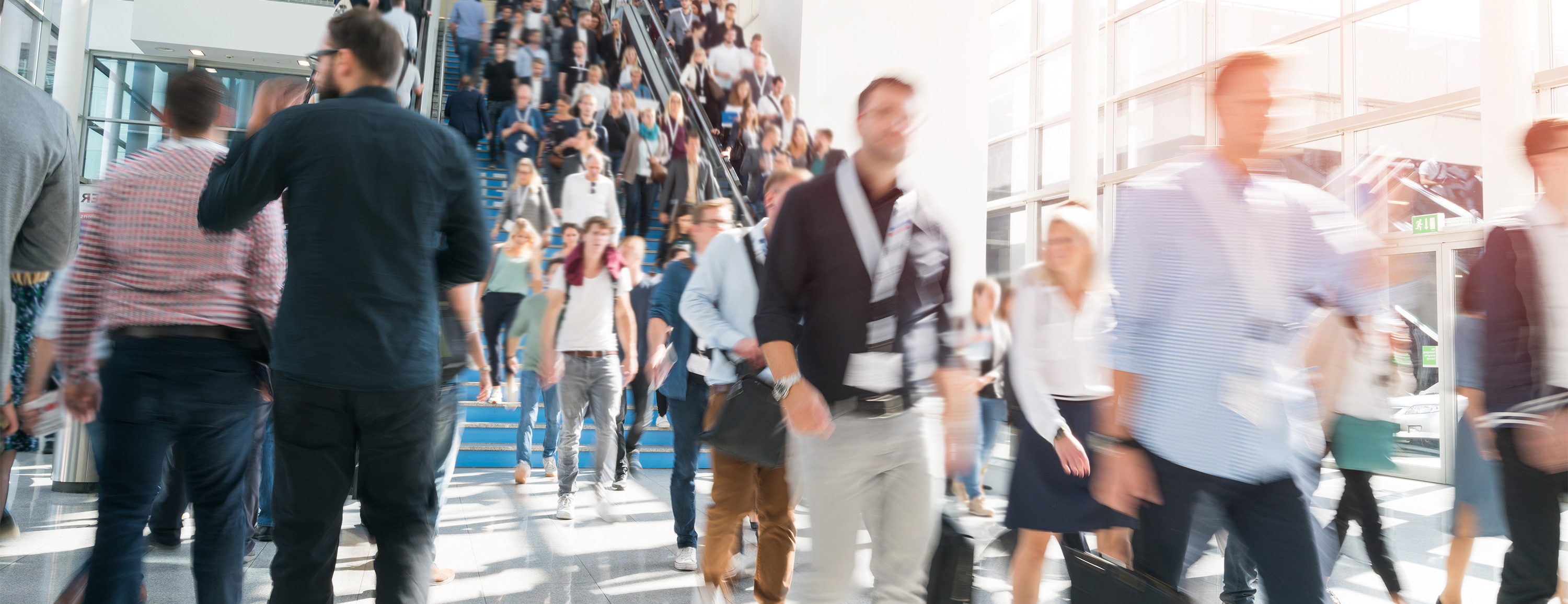 Crowd of people walking down stairs in a bright, modern building