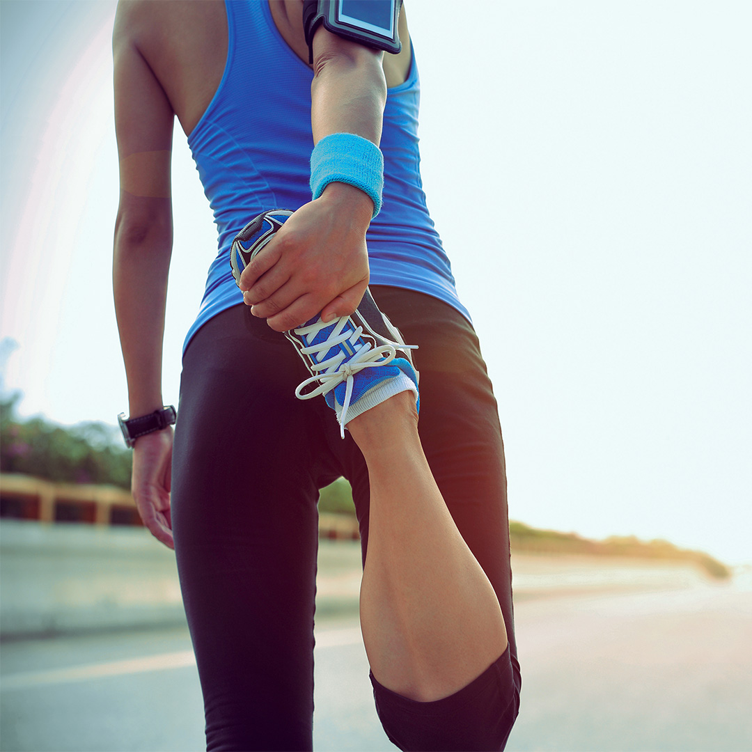 Person stretching leg while wearing athletic clothing and shoes
