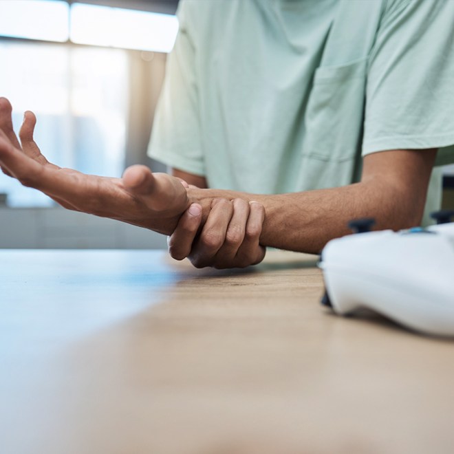 Person holding their wrist in discomfort while gaming